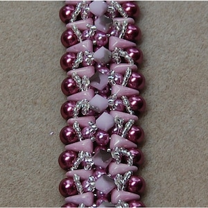 以下が含まれることがあります： 濃いピンク色と薄いピンク色のビーズが交互に並んだビーズブレスレット。 ブレスレットは丸、三角、四角のビーズで作られており、銀色のワイヤーで繋がれています。