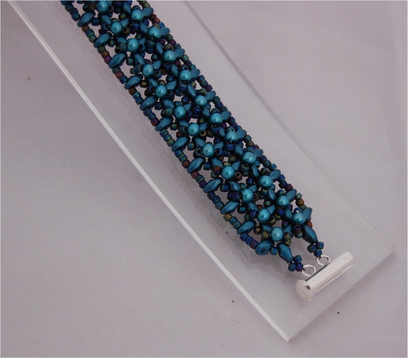 Pode incluir: Um bracelete de contas azul turquesa com um fecho prateado. O bracelete &eacute; feito com m&uacute;ltiplos fios de contas em um padr&atilde;o repetitivo.