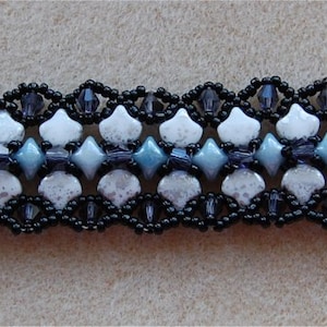 May include: A black and white beaded bracelet with a silver clasp. The bracelet features a repeating pattern of white and blue beads.