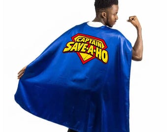 May include: A vibrant blue superhero cape featuring a yellow and red shield-shaped emblem on the back. The emblem contains the bold text CAPTAIN SAVE-A-HO in yellow letters with a red outline, set against a yellow background with a red border.