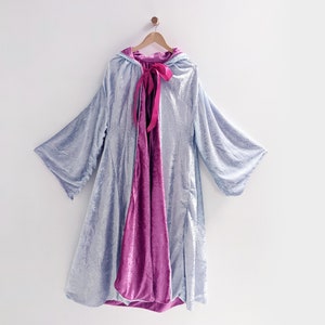 May include: A light blue hooded cape with a pink velvet lining and a pink satin ribbon tied at the neck.