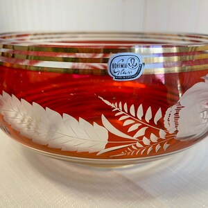 May include: A red glass bowl with a gold rim and etched floral design. The bowl has a label that reads "BOHEMIA Glass Made in Czechoslovakia."