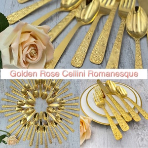 May include: A set of gold-plated flatware with a rose design. The flatware is arranged in a circle and includes forks, knives, and spoons. The flatware is called "Golden Rose Cellini Romanesque".