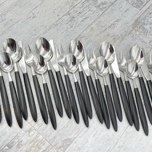 May include: A set of silver cutlery with black handles. The set includes forks, knives, and spoons.