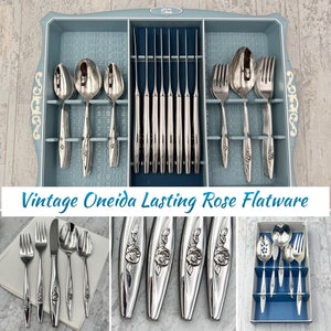 May include: Vintage Oneida Lasting Rose flatware in a blue tray. The set includes knives, forks, spoons, and serving pieces. The silverware features a rose design.