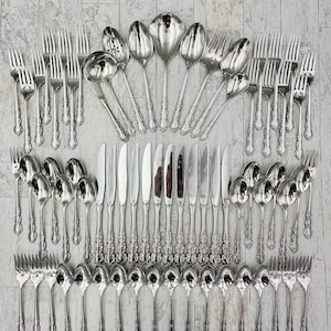 May include: A set of silver flatware with ornate handles. The set includes forks, knives, spoons, and serving spoons.