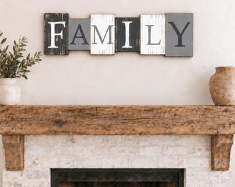Könnte beinhalten: Ein Wand-Holzschild mit dem Wort FAMILY, das auf einzelnen rechteckigen Blöcken geschrieben steht. Die Buchstaben sind abwechselnd in Weiß und Dunkelgrau auf verwitterten Holzpaneelen mit einer abgenutzten Oberfläche gemalt.
