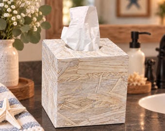 Könnte beinhalten: Ein quadratischer Taschentuchbox-Bezug mit einem hellen, strukturierten Holzspanmuster und weißem Finish. Die Box besteht aus gepressten Holzspänen und zeigt ein natürliches, geschichtetes Erscheinungsbild mit sichtbarer Maserung und hellbraunen Tönen.
