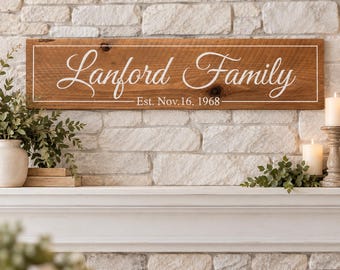 Könnte beinhalten: Ein rechteckiges Holzschild mit natürlicher brauner Oberfläche und weißem Rand. Der Text "Lanford Family" ist in weißer Schreibschrift gehalten, darunter steht "Est. Nov. 16, 1968" in einer kleineren, weißen serifenlosen Schrift.
