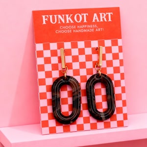 May include: A pair of oval-shaped earrings with a marbled brown pattern, hanging from gold-colored bars. The earrings are displayed on a red and pink checkered card with the text "FUNKOT ART" and "CHOOSE HAPPINESS, CHOOSE HANDMADE ART!"