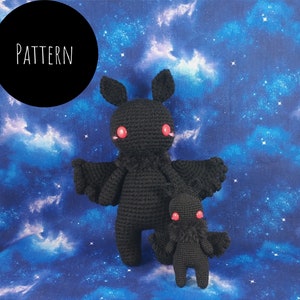 May include: Two black crochet moth dolls with red eyes and pink cheeks, one large and one small, against a starry blue backdrop. The word "PATTERN" is in white text inside a black circle in the upper left corner.
