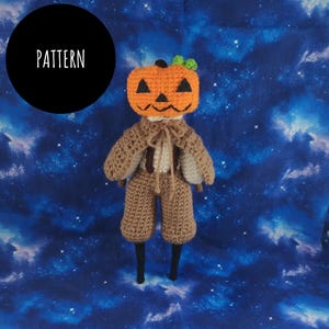 May include: A crocheted pumpkin doll with a brown body, brown pants, and a black hat. The doll is standing on a blue background with white stars.