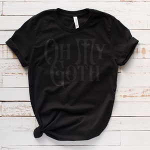 May include: Black t-shirt with the text "Oh My Goth" in a gothic font.