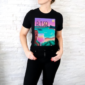 May include: Black t-shirt with a colourful graphic design featuring a tropical scene with a cocktail glass and the text "Visit Risa The Island of Aloha".