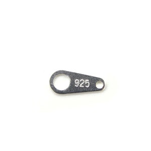 Puede incluir: Un charm de metal plateado con un agujero redondo y el número "925" estampado en él.