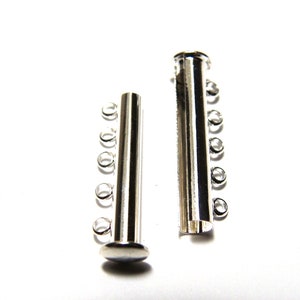Peut inclure: Deux connecteurs en métal argenté pour un collier ou un bracelet. Chaque pièce a cinq boucles d'un côté et un cylindre plein de l'autre.
