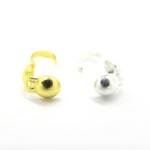 Op de afbeelding: Twee metalen sluitingen, een gouden en een zilveren, met een ronde bal aan het einde. De sluitingen zijn bedoeld voor het maken van sieraden.