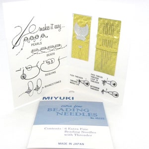 Può includere: Un pacchetto di sei aghi per perline extra fini con un infila-ago. La confezione è blu e bianca con il testo "MIYUKI extra fine BEADING NEEDLES No. H522/E" e "Contents: 6 Extra Fine Beading Needles with Threader MADE IN JAPAN".