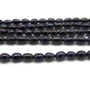 May include: A strand of black freshwater pearls, with a slight iridescent sheen. The pearls are oval shaped and have a smooth, polished finish.