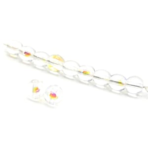 May include: Clear, iridescent glass beads strung on a wire, with two loose beads. The beads are round and have a shimmering, rainbow-like effect. The wire has a small loop at the end. The beads are suitable for jewellery making.