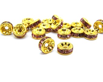 May include: Gold-colored spacer beads with a ring of small, purple rhinestones. The beads have a flower-like design around the central hole. These decorative beads are ideal for jewelry making and crafting projects.