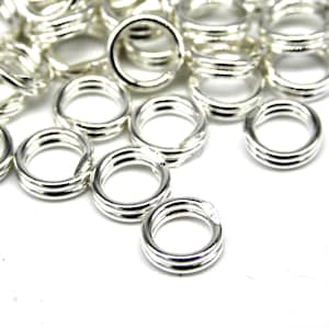 May include: A pile of silver jump rings, a type of jewellery finding used for connecting chains, cords, and other jewellery components.