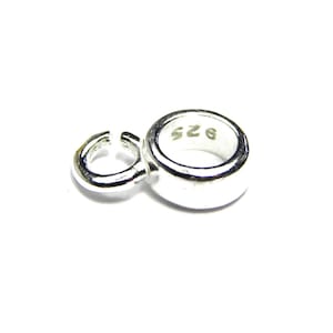 Puede incluir: Anillo de metal plateado con un anillo de salto adjunto. El anillo tiene la inscripci&oacute;n "925" en el interior.