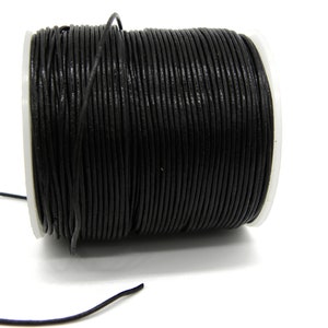Puede incluir: Un carrete de cordón de cuero negro, enrollado firmemente y listo para proyectos de artesanía.