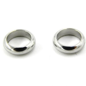 Könnte beinhalten: Zwei polierte, silberfarbene Ringe werden vor einem weißen Hintergrund gezeigt. Die Ringe sind kreisförmig, mit einer glatten, abgerundeten Oberfläche. Die Ringe scheinen aus Metall zu sein und haben eine glänzende, reflektierende Qualität.