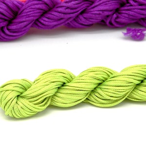 May include: Close-up of colourful embroidery floss in neon green, purple, and pink. The floss is tightly wound, showing its texture and sheen. Suitable for various craft projects, including embroidery and friendship bracelets.