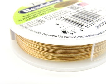May include: A spool of gold-colored beading wire. The label reads "Beadalon", "Beading Wire", "Fil Pour Bijoux", "Alambre Para Bisuteria", "Souple et Flexible", "018 in", "12 m", "Intended for adult use only. Pour usage adulte seulement. Para uso exclusivo de adultos."