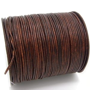 Può includere: Una bobina di cordoncino in pelle marrone scuro, ben avvolta. Il cordoncino rotondo ha un aspetto naturale e strutturato. Il ricco colore marrone contrasta con uno sfondo bianco, evidenziando la qualità del materiale. Ideale per la creazione di gioielli.