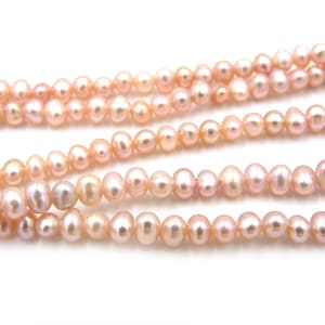 May include: A strand of pink freshwater pearls. The pearls are round and have a smooth, lustrous finish.