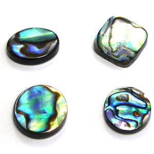 Peut inclure: Quatre boutons en nacre d'ormeau irisés de différentes formes et tailles. Les boutons sont ronds, ovales et carrés. La nacre présente un reflet irisé bleu, vert et or.
