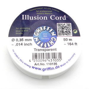 Könnte beinhalten: Eine Spule transparentes Nylon-Illusion-Cord für die Schmuckherstellung. Das Etikett trägt die Aufschrift "Illusion Cord" und das Griffin-Logo. Der Faden hat einen Durchmesser von 0,35 mm und ist 50 m lang. Auf dem Etikett steht auch "zum Auffädeln von Perlen und Schmuck".