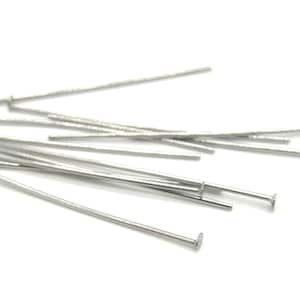 May include: A close-up of a pile of silver head pins. The pins are thin and have a small, flat head.