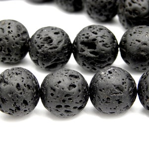 Peut inclure: Un brin de perles en roche volcanique noire. Les perles sont rondes et ont une surface rugueuse et texturée.