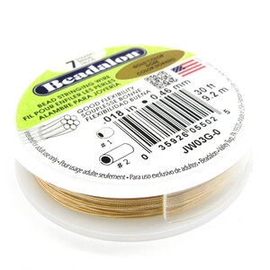 May include: Gold colored Beadalon bead stringing wire, 0.018 inches in diameter, 30 feet long. The spool is labeled with the brand name, size, and material.  The label also includes the text "Good Flexibility" and "Adult Use Only".