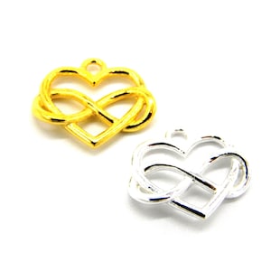 Pode incluir: Dois pingentes de coração infinito, um dourado e outro prateado. Os pingentes têm a forma de um coração com um símbolo de infinito dentro.