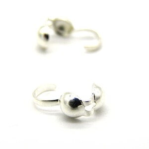 May include: Two silver-toned metal clasps for jewellery making. The clasps are round and have a small loop on one side.