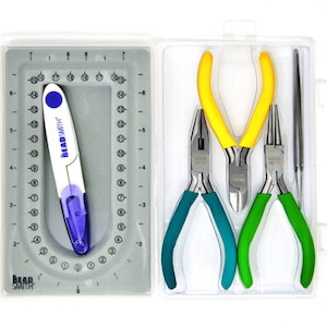 Op de afbeelding: Een transparante kunststof koffer met een set kralen gereedschap. De gereedschappen omvatten een tang met gele handvatten, een tang met groene handvatten, een tang met blauwe handvatten en een kralen gereedschap met een wit en paars handvat. Het kralen gereedschap heeft de tekst "BeadSmith" erop gedrukt.