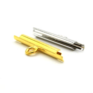 May include: Two metal clasps, one gold and one silver, for jewelry making. The gold clasp has a loop on one end and a flat end on the other. The silver clasp is a tube shape with a small opening on one end.