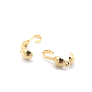 May include: Two gold-toned metal clasps for jewelry making. Each clasp has a rounded, half-circle shape with a small opening on one side.