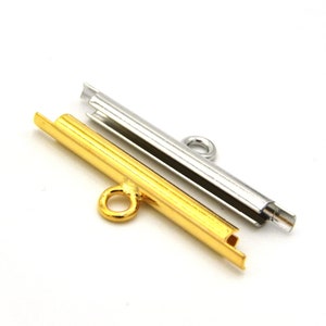 May include: Two metal bead caps, one gold and one silver, with a loop at one end. The caps are designed to hold beads in place.