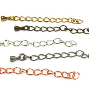 Op de afbeelding: Vijf verschillende kettingverlengers met een traanvormig uiteinde. De kettingen zijn goud, brons, zilver, zwart en koper.