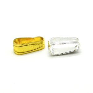 May include: Two small, rectangular metal jewelry findings. One is gold-colored with a ridged design, and the other is silver-colored. Both are on a white background. These findings are used in jewelry making.