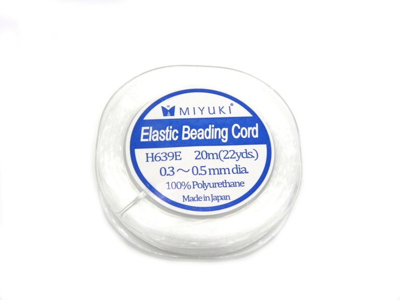 May include: A white spool of elastic beading cord from Miyuki. The label reads "Elastic Beading Cord", "H639E 20m(22yds)", "0.3~0.5mm dia.", "100% Polyurethane", and "Made in Japan".