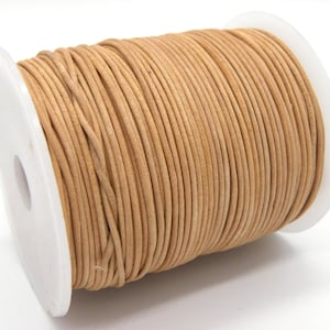 Op de afbeelding: Een spoel met tan lederen koord, strak gewikkeld rond een witte plastic spoel. Het koord is glad en lijkt van goede kwaliteit te zijn.