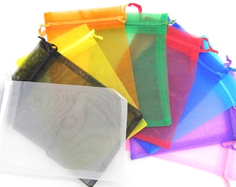 May include: A collection of colorful, sheer organza gift bags in various colors, including orange, yellow, green, red, blue, and purple. Each bag has a drawstring closure and a small loop at the top.