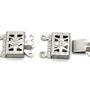 Puede incluir: Un conjunto de tres cierres de joyería plateados. Cada cierre tiene un cuerpo rectangular con un diseño floral decorativo y un mecanismo de cierre seguro. Los cierres están diseñados para la fabricación y reparación de joyas.
